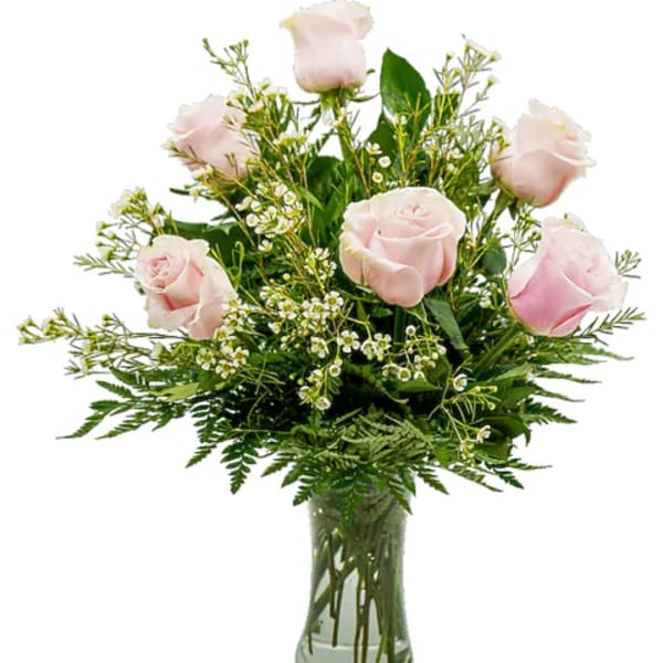 Light pink roses arranged in a clear glass vase with greenery