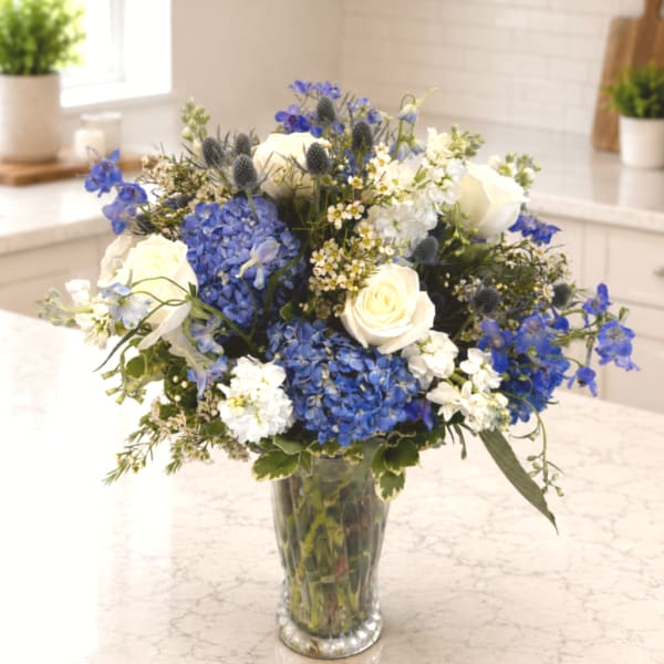 Blue and white flower arrangement in a clear glass vase