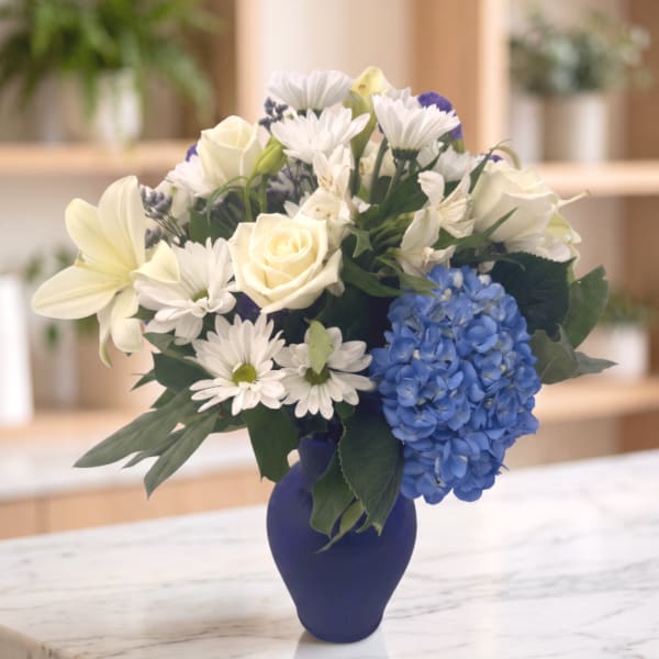 White and blue flower arrangement in a dark vase
