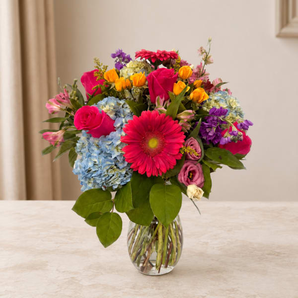 Mixed bouquet of bright flowers in a clear glass vase