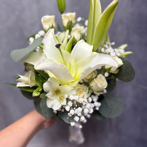 White lily and rose bouquet with baby's breath in a clear vase