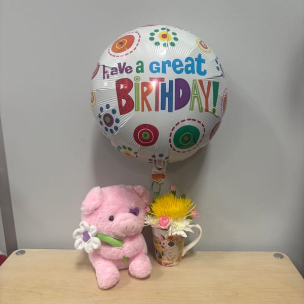 Pink plush pig with a birthday balloon and small flower mug arrangement