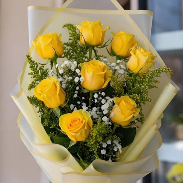 Bouquet of yellow roses with white baby's breath in pale wrapping