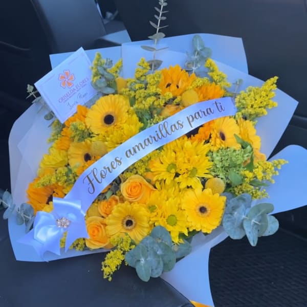 Yellow bouquet with gerbera daisies and roses wrapped in pale blue paper