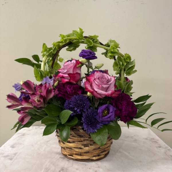 Basket arrangement of pink and purple flowers with greenery