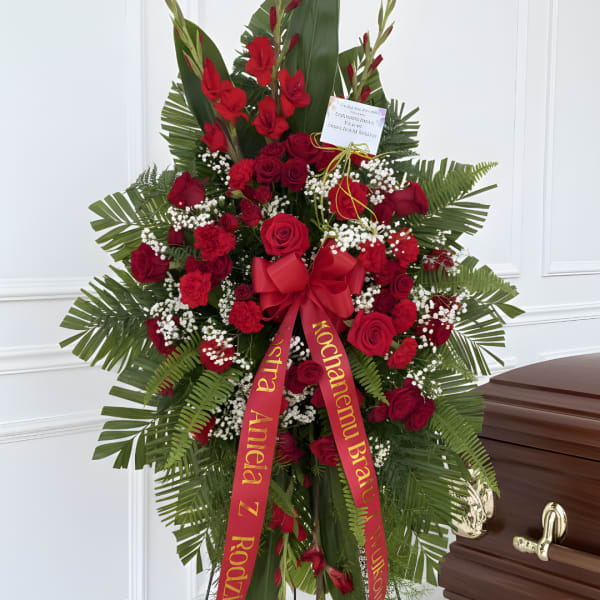 Standing red rose funeral spray with ribbon on a casket
