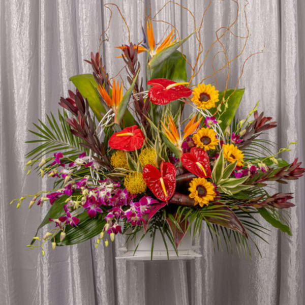 Tropical flower arrangement with red anthuriums, sunflowers, and orchids