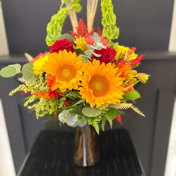 Bright bouquet of sunflowers and red roses in a glass vase