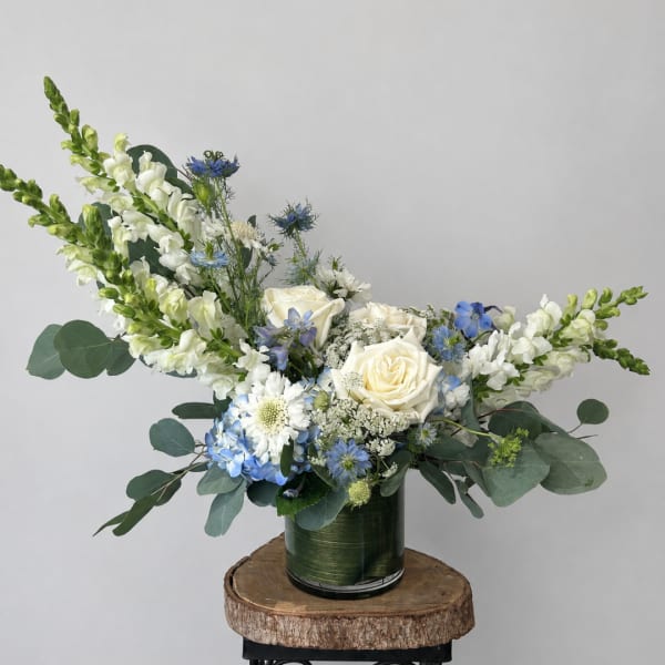 White roses and blue flowers in a green vase