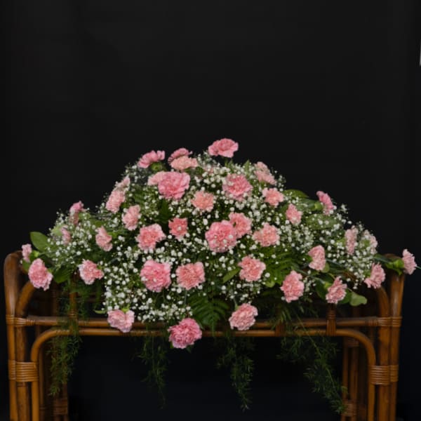 Pink carnations arranged in a wicker basket with baby's breath