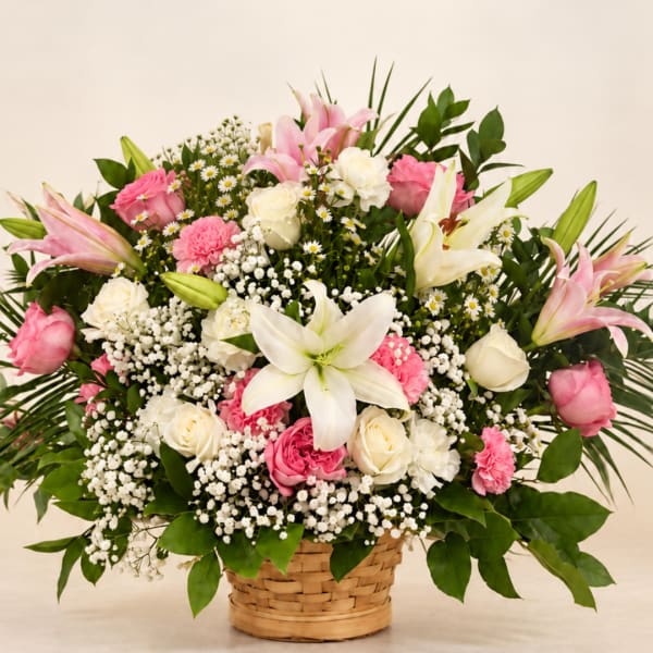 Pink and white floral arrangement in a woven basket