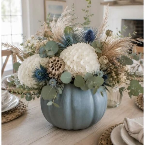 White floral arrangement in a blue pumpkin vase with dried accents