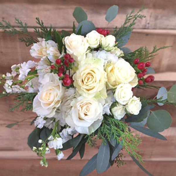White rose bridal bouquet with red berries and greenery