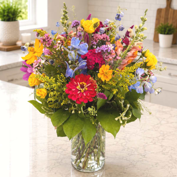 Colorful mixed bouquet in a clear glass vase on a countertop