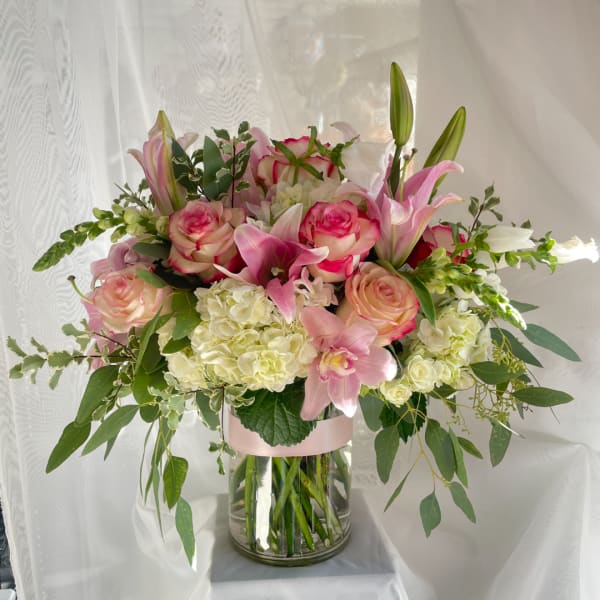 Pink roses and lilies arranged in a clear glass vase