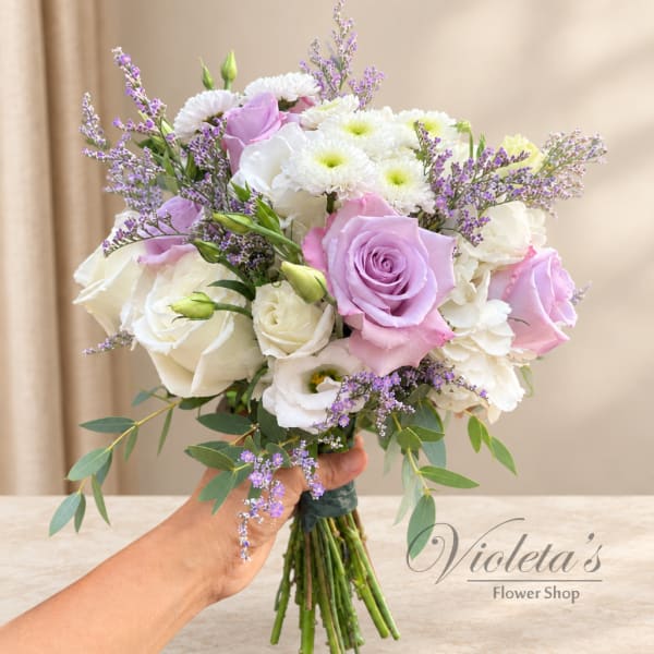 Handheld bouquet of white and lavender roses with white daisies and purple filler flowers