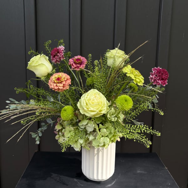 Mixed bouquet of roses and zinnias in a white vase