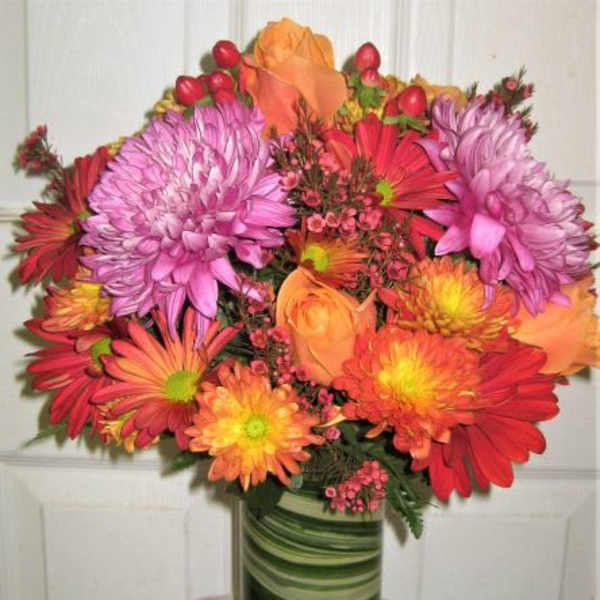 Colorful bouquet of pink, orange, and red flowers in a green glass vase