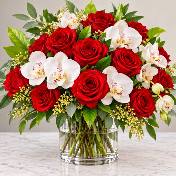 Red roses and white orchids in a clear glass vase