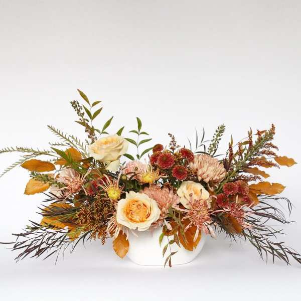 Autumn floral arrangement in a white vase with cream roses and mums