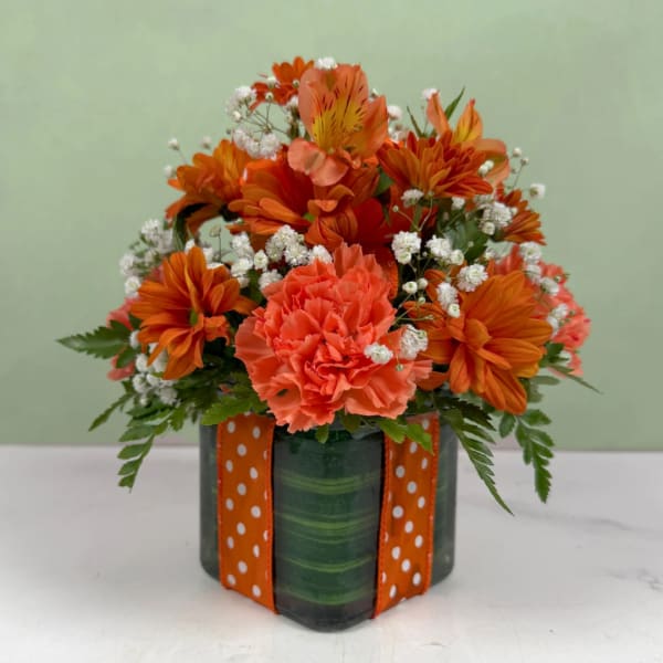 Orange bouquet in a green vase with a polka-dot ribbon