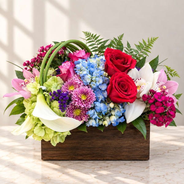 Mixed bouquet with roses, hydrangeas, orchids, lilies, and chrysanthemums in a wooden box