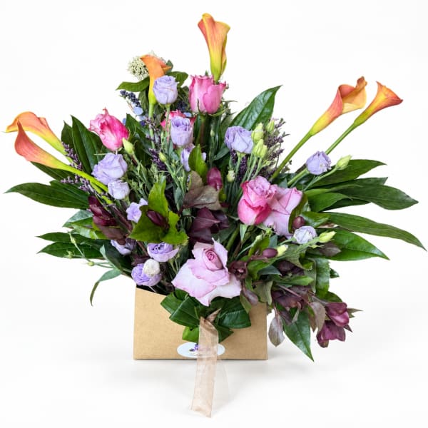 Mixed bouquet with pink roses, lavender blooms, and orange calla lilies in a box