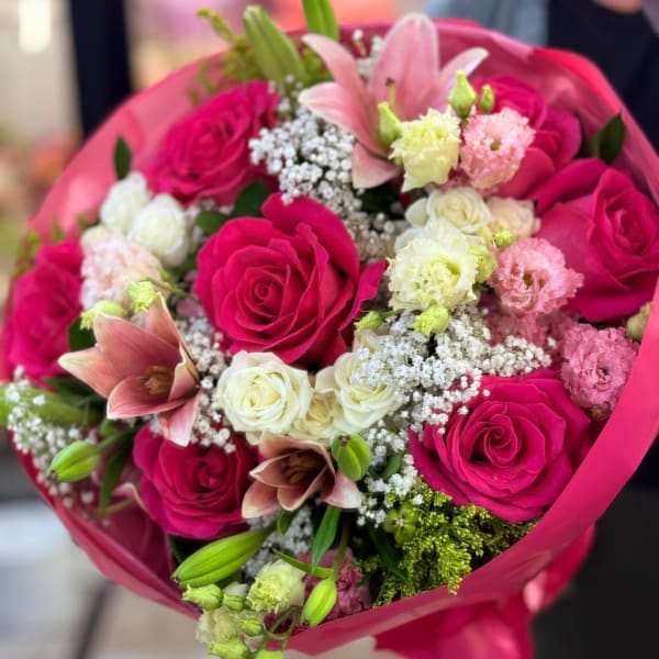 Bouquet of hot pink and white roses with pink lilies in bright wrapping