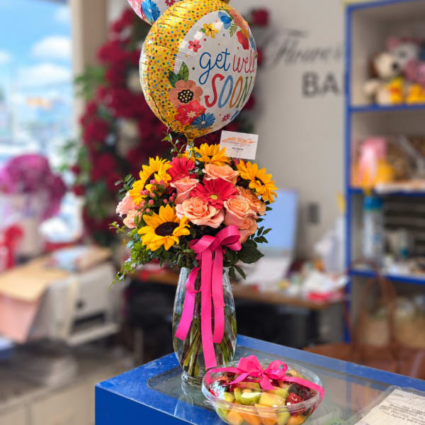 Bouquet of mixed flowers in a glass vase with a get well balloon