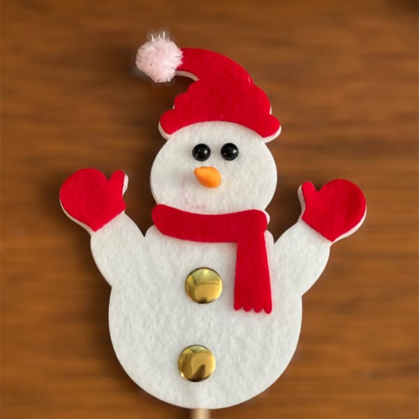 Snowman decoration with red hat, scarf, and mittens on a stick