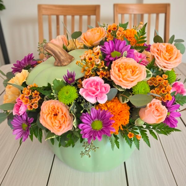 Pumpkin-shaped vase filled with peach, purple, pink, and orange flowers