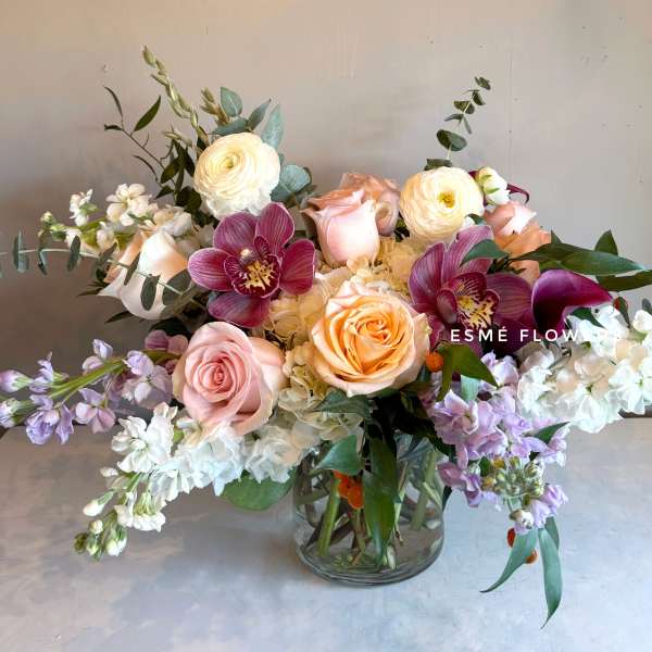 Mixed bouquet of roses, orchids, and white blooms in a glass vase
