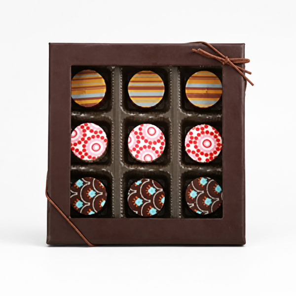 Box of assorted chocolates with patterned tops in a brown gift box