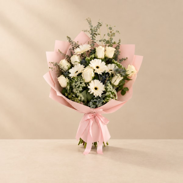 Pink-wrapped bouquet of white roses and daisies with a satin ribbon