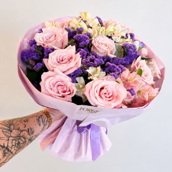 Pink roses and purple filler flowers wrapped in lavender paper