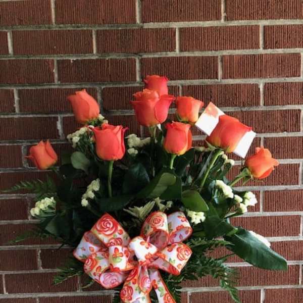 Orange rose bouquet in a glass vase with a patterned ribbon