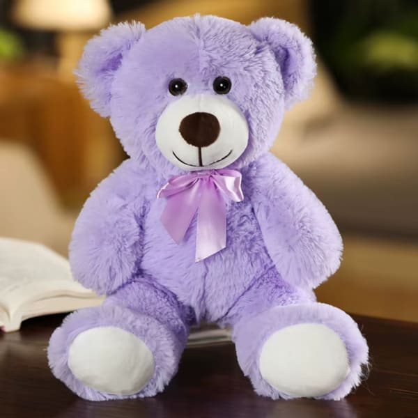 Lavender teddy bear with a satin ribbon sitting on a table