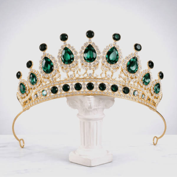 Gold tiara with green gemstones on a white pedestal