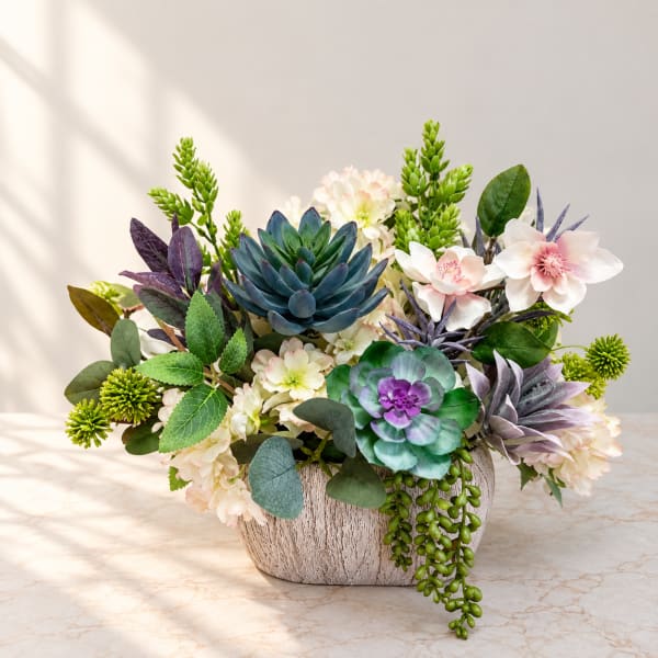 Mixed floral arrangement in a textured white vase with succulent accents