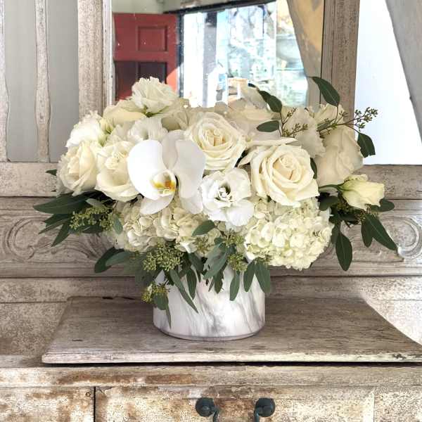 White roses and orchids arranged in a marble vase