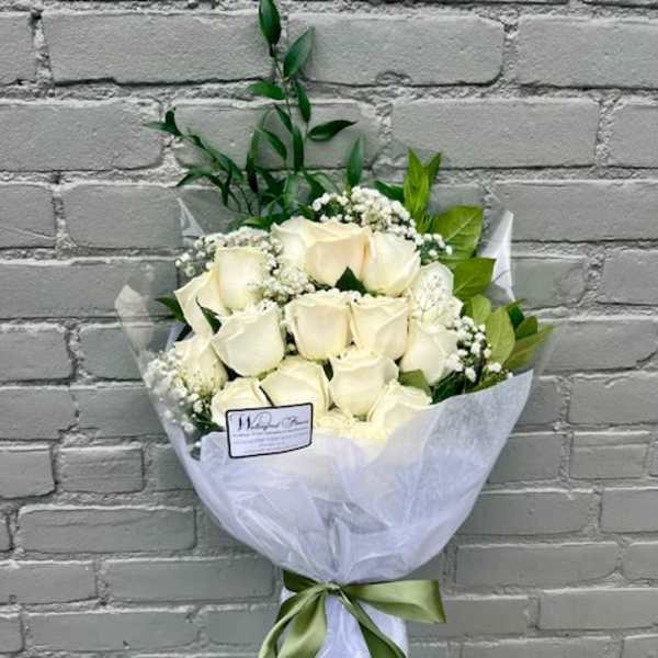 Bouquet of white roses wrapped in white paper with a green ribbon