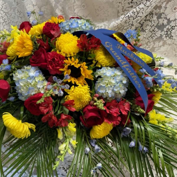 Large mixed flower arrangement with red roses, yellow mums, and blue hydrangeas
