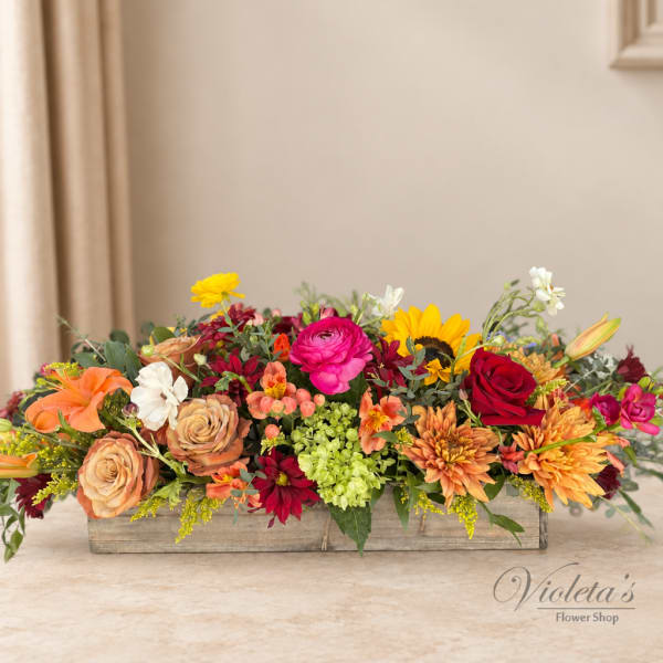 Low rectangular flower arrangement with roses, daisies, and sunflowers in a wooden box