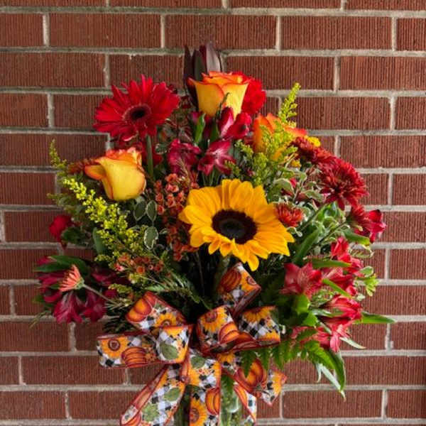 Colorful bouquet of sunflowers, roses, and gerbera daisies in a glass vase