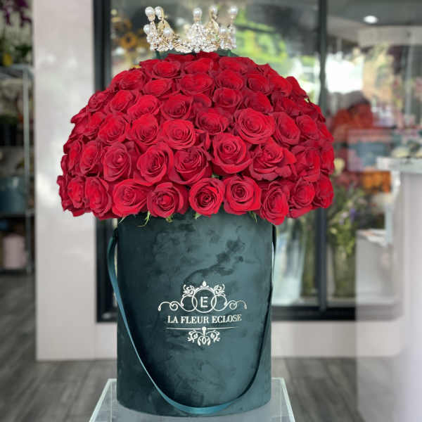 Large dome of red roses in a velvet hatbox with a jeweled crown topper