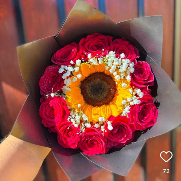 Bouquet of red roses around a sunflower with white baby's breath