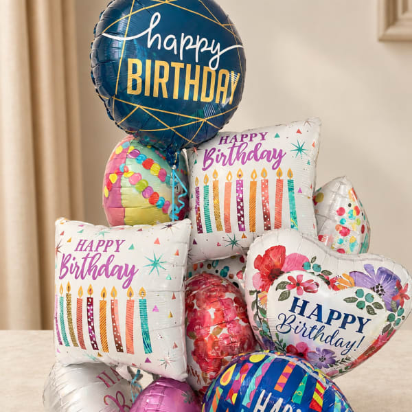 Cluster of colorful birthday balloons with printed messages and candles