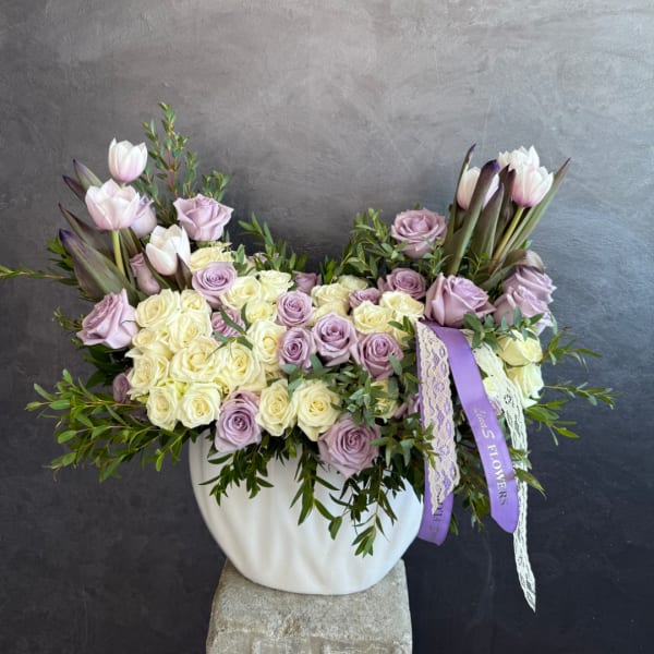 Lavender and cream roses with pale tulips in a white vase