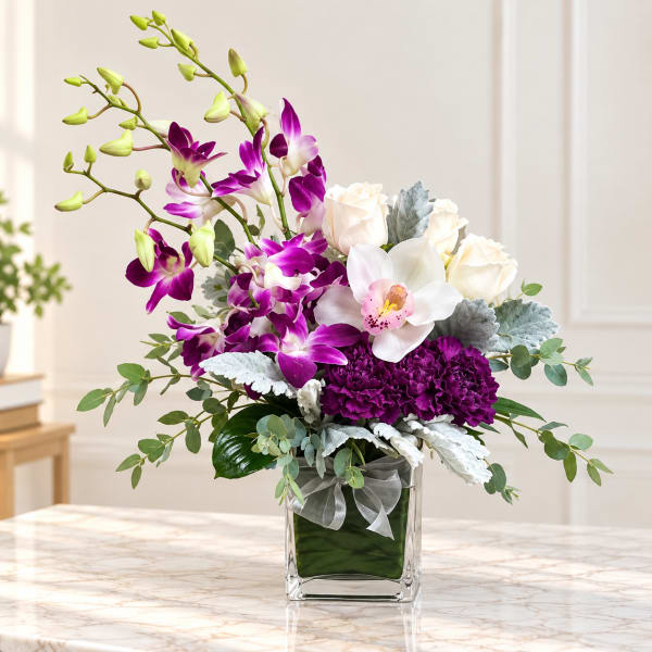 Purple orchids and white roses arranged in a glass vase
