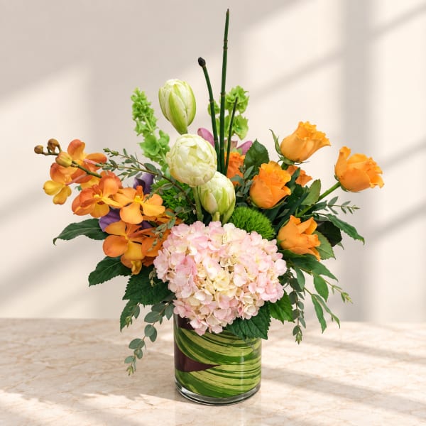 Orange roses and pink hydrangeas in a glass vase